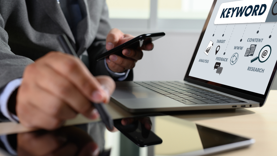 A person in a suit using a laptop to search for Amazon keywords