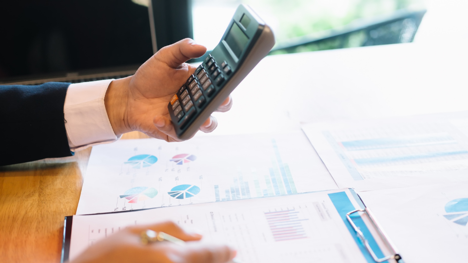 A person considering their pricing strategy with financial documents and a calculator