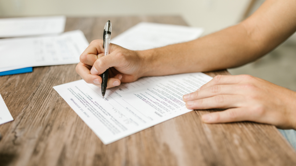A person using a pen to fill out a brand registry form