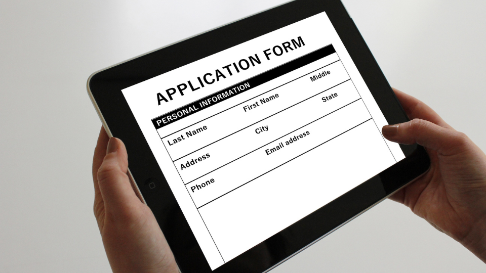 A person filling out an application form on a tablet