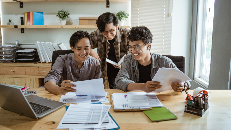 Three individuals sitting at a desk looking at KPIs