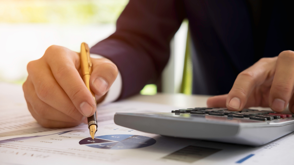A person calculating costs using a calculator and pen