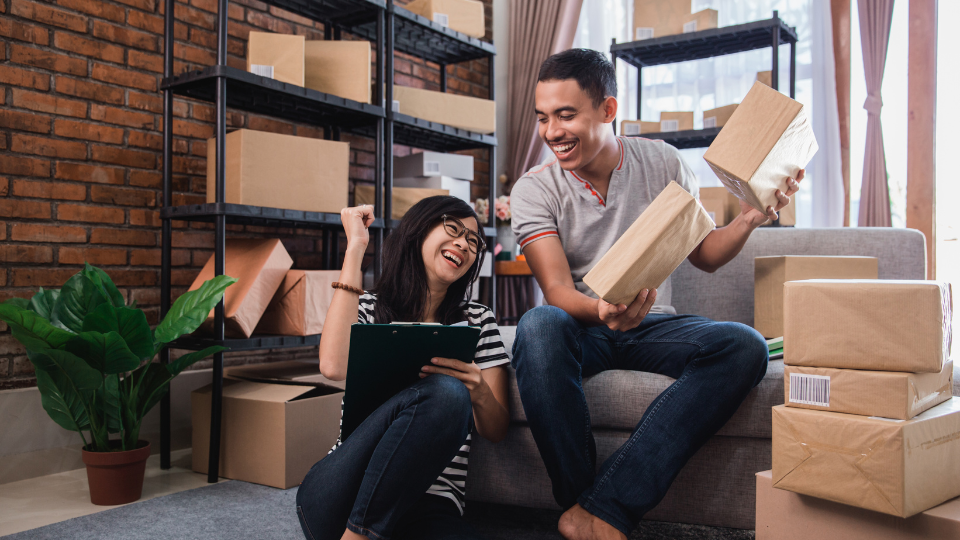 Two ecommerce professionals helping each other, with boxes all around them