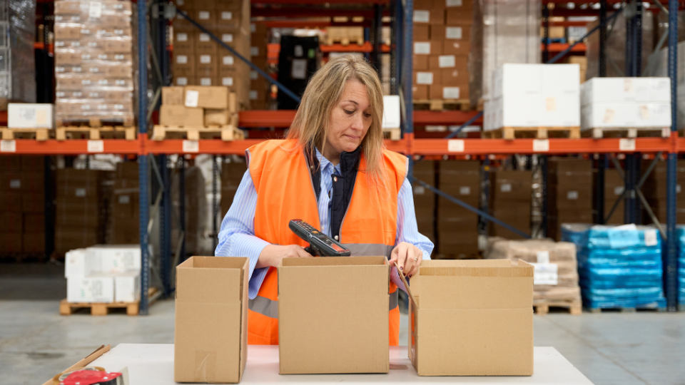 A person scanning barcodes on boxes with a scanner