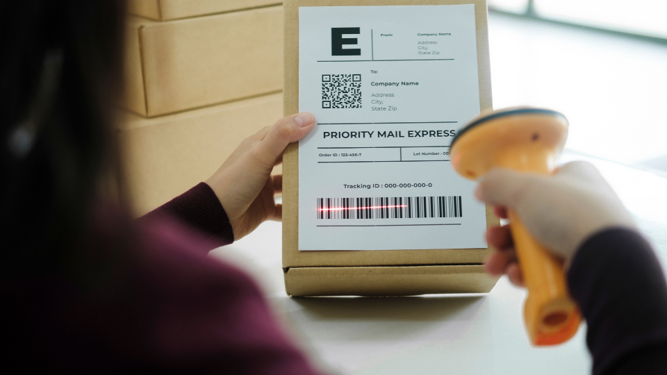 A person holding a package and scanning its barcode with a scanner
