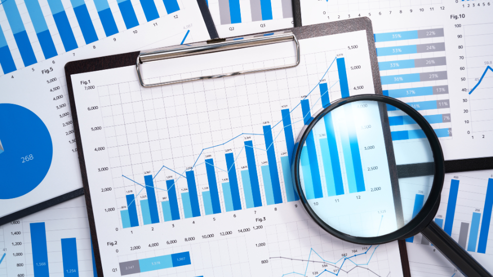 A magnifying glass placed on top of graphs and charts