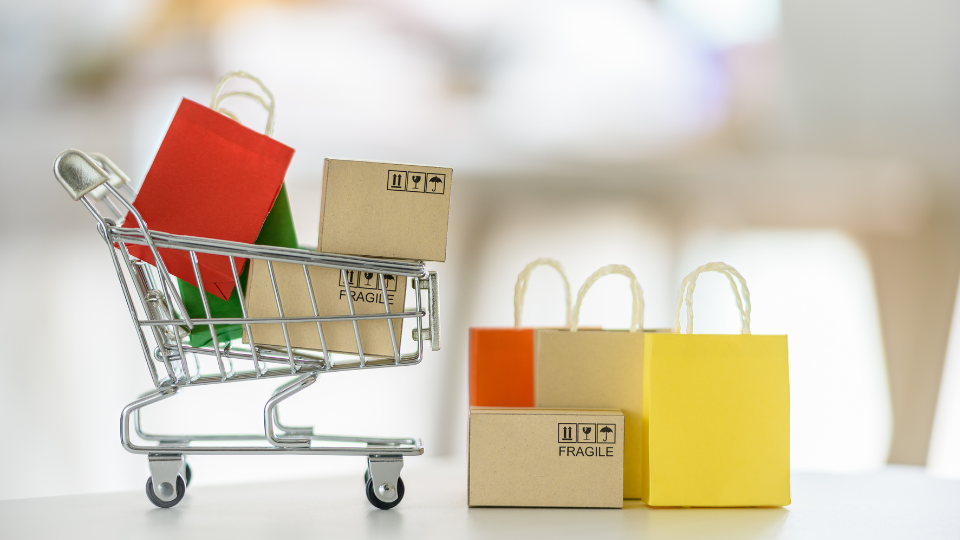 A mini shopping cart filled with boxes next to mini shopping bags