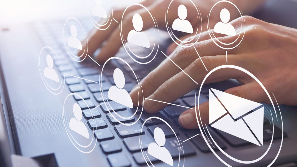 A close up of two hands typing on a laptop, with email icons overlaid on the image