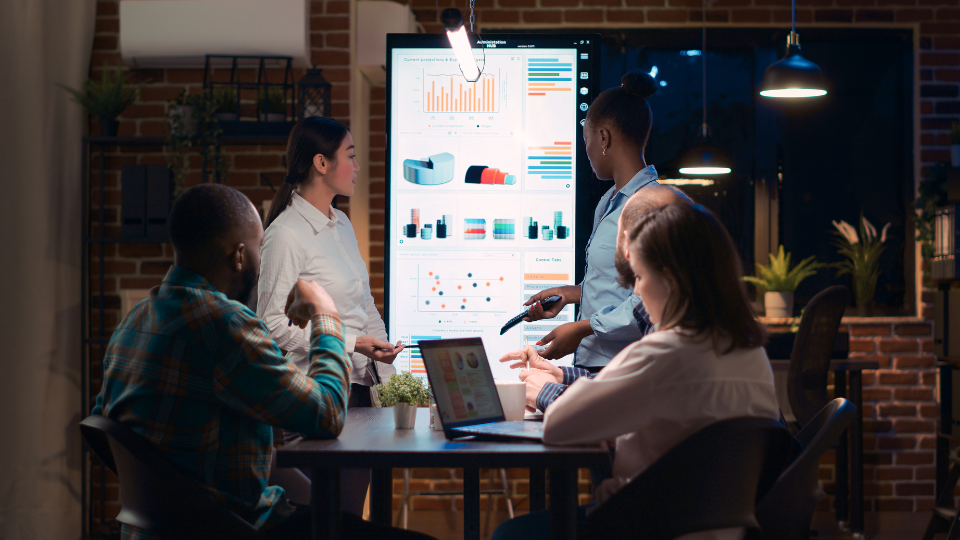 People sitting at a table analyzing analytics on a large screen