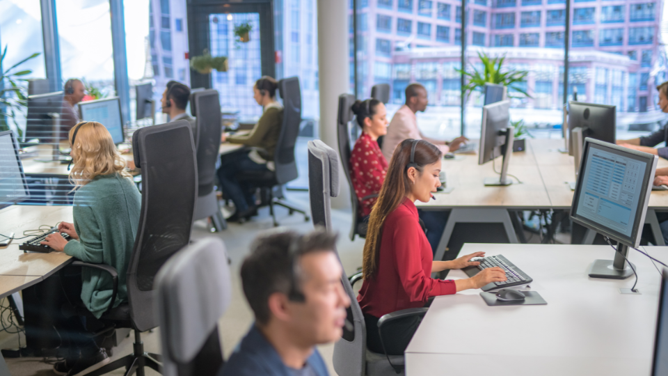 Customer service representatives work at their desks using headsets