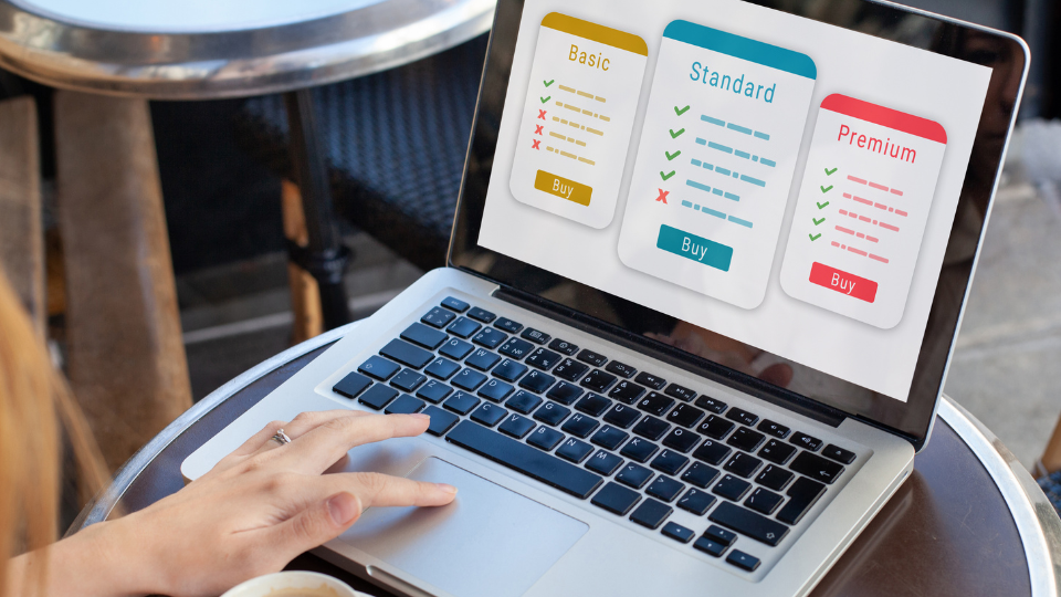 A business person sitting at a table with a laptop looking at different subscription plans