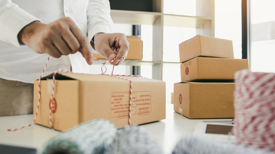 An ecommerce business person wraps a box to prepare for shipping